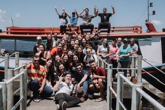 Grupo de missionários reunido em um píer, ao lado de um barco